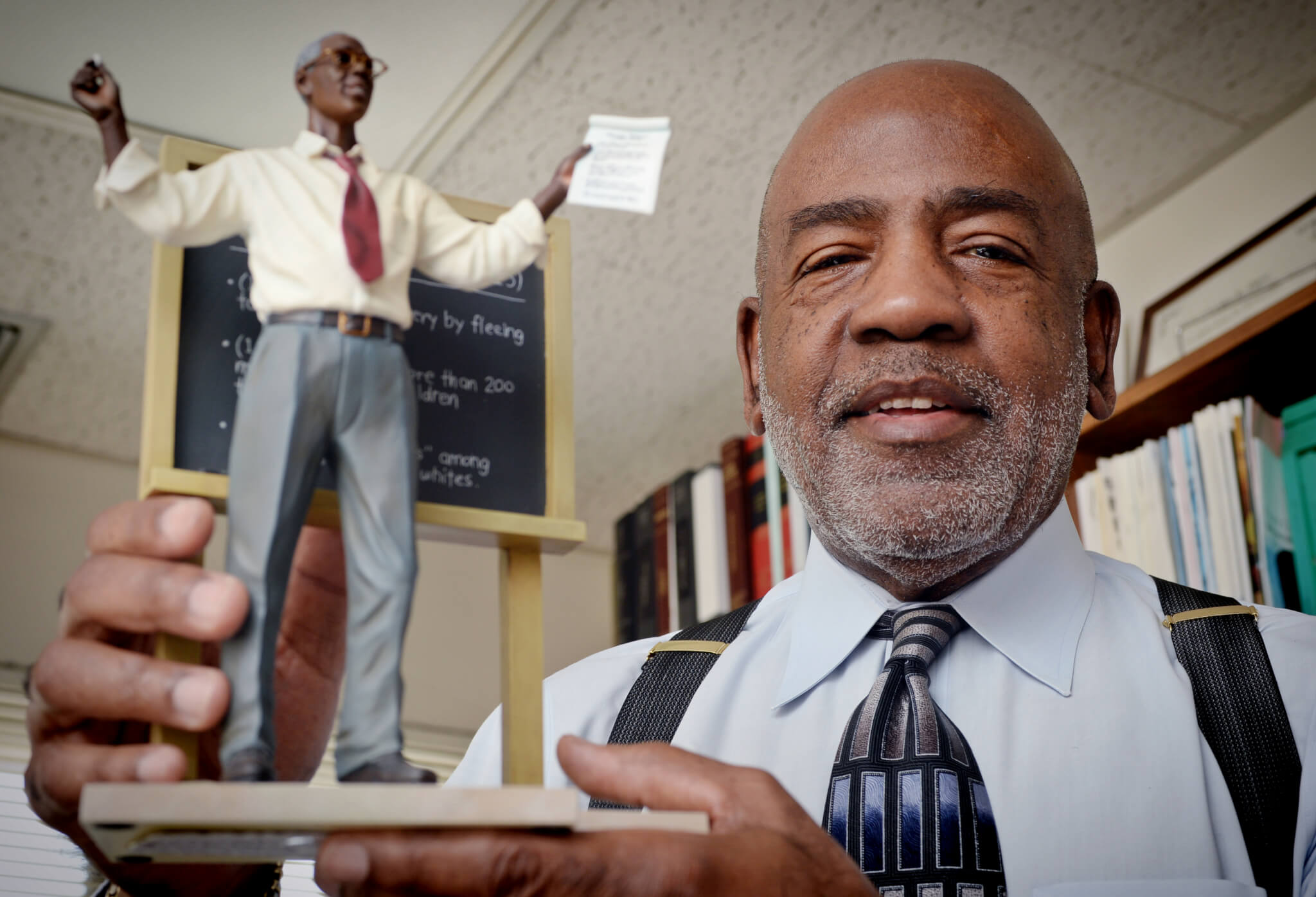 Charles Daye holds up a figurine of a professor