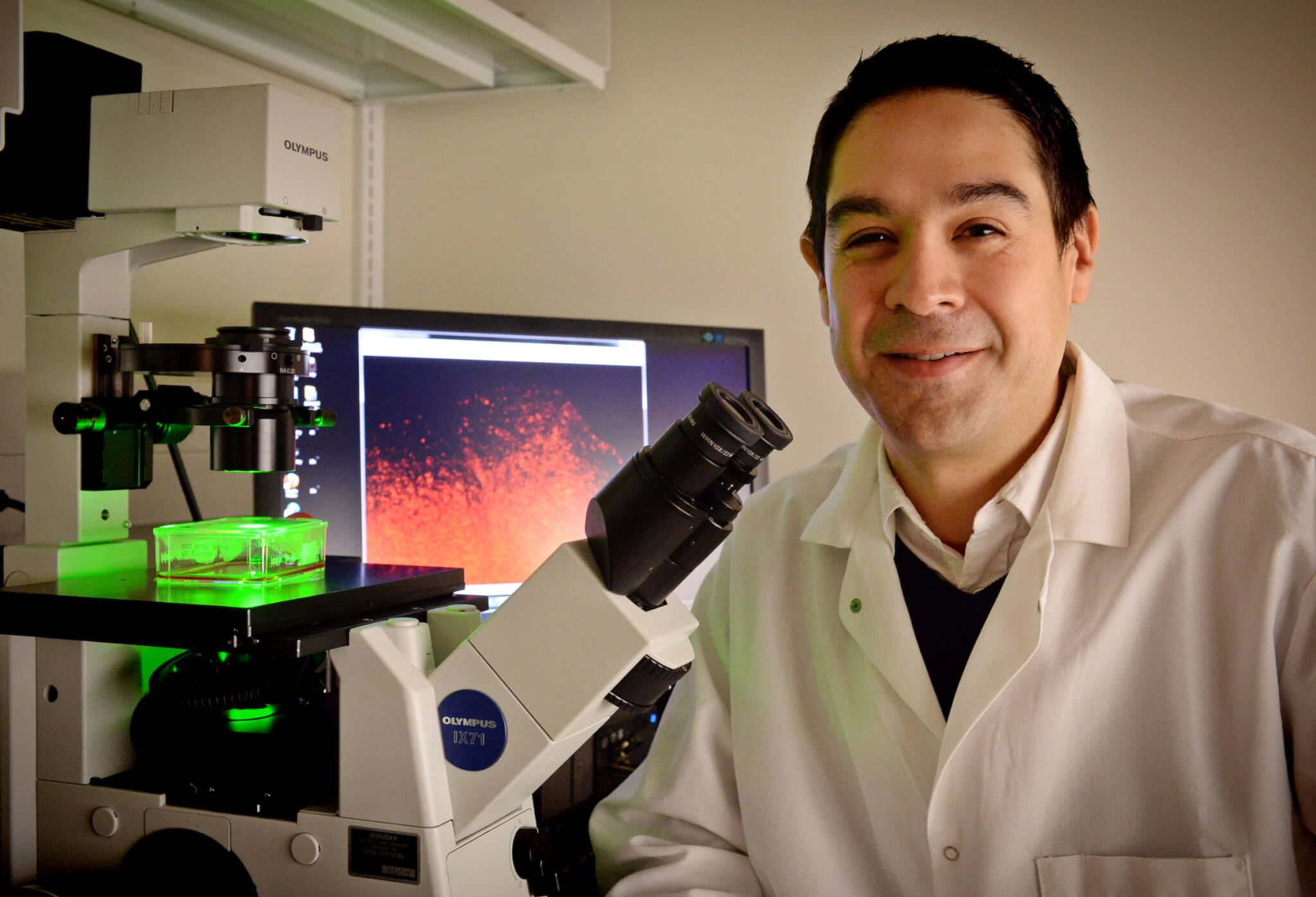 Dr. Shawn Hingtgen sits next to microscope