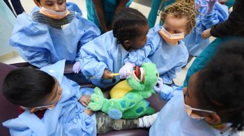 Children practice dental hygiene on a stuffed T-Rex