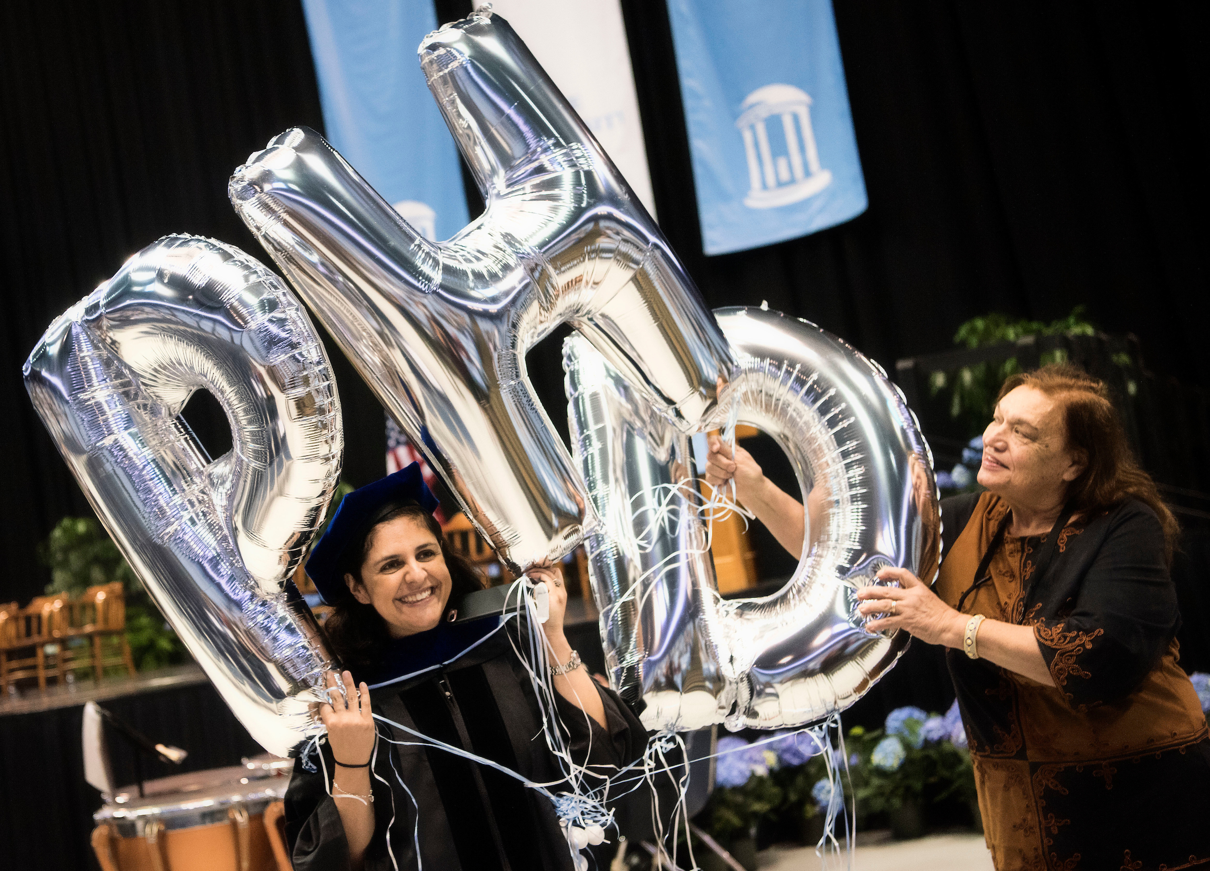 Doctoral Hooding candidates hold balloons spelling P.H.D.