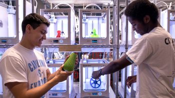 Two students use a 3D printer.