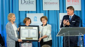 Amy Stursberg, Chancellor Carol L. Folt and Judith Cone hold a framed certificate