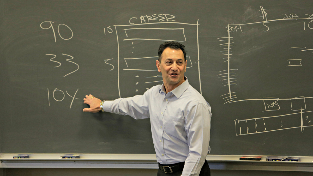 Markus Saba points to a chalkboard during a lecture.