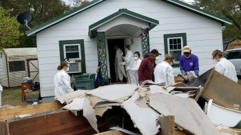 Students remove drywall from a house damaged by flooding.