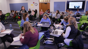 Teaching professor Meredith Petschauer lectures in a classroom with no desks.
