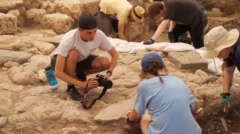 A male student takes a photo at the Huqoq dig site.