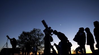 People look through telescopes in the evening.
