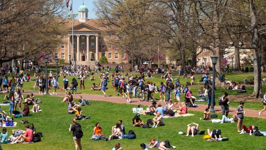 Wide shot of Polk Place with students scattered across the lawn