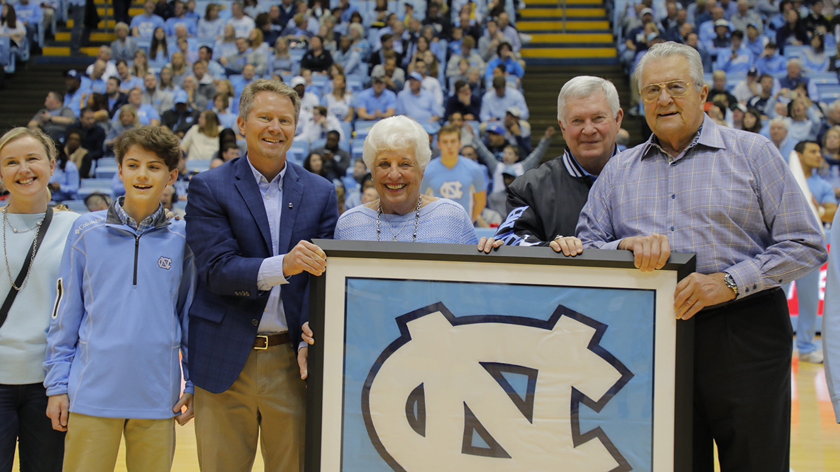 Stallings and Chancellor Guskiewicz hold a UNC banner in front of basketball fans