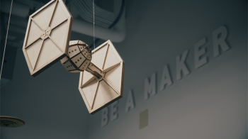 A wooden model of a Star Wars TIE figher hangs from a ceiling.