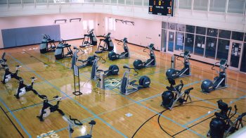 A basketball court with cardio workout equipment spread out.