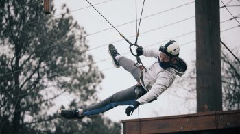 A student swinging from a rope course.