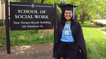 Daniela Ceron in her cap and gown by the School of Social Work.