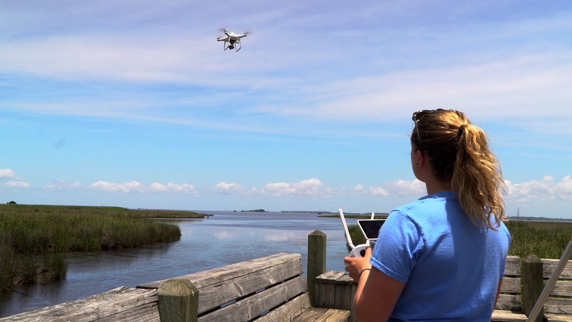 A woman flies a drone over water