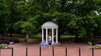 A student poses for photos by the Old Well.