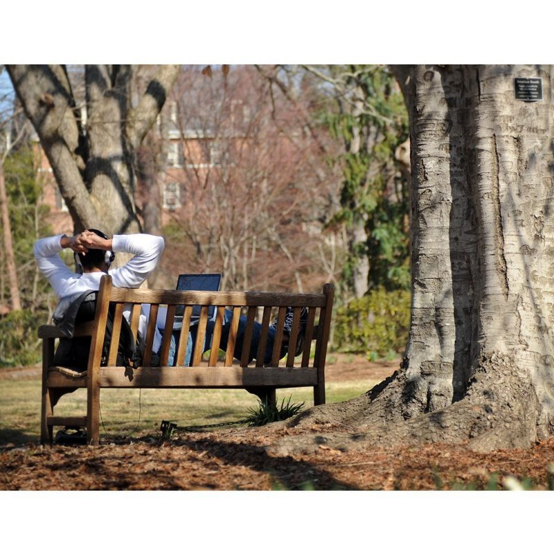 A person sits on a bench outside.