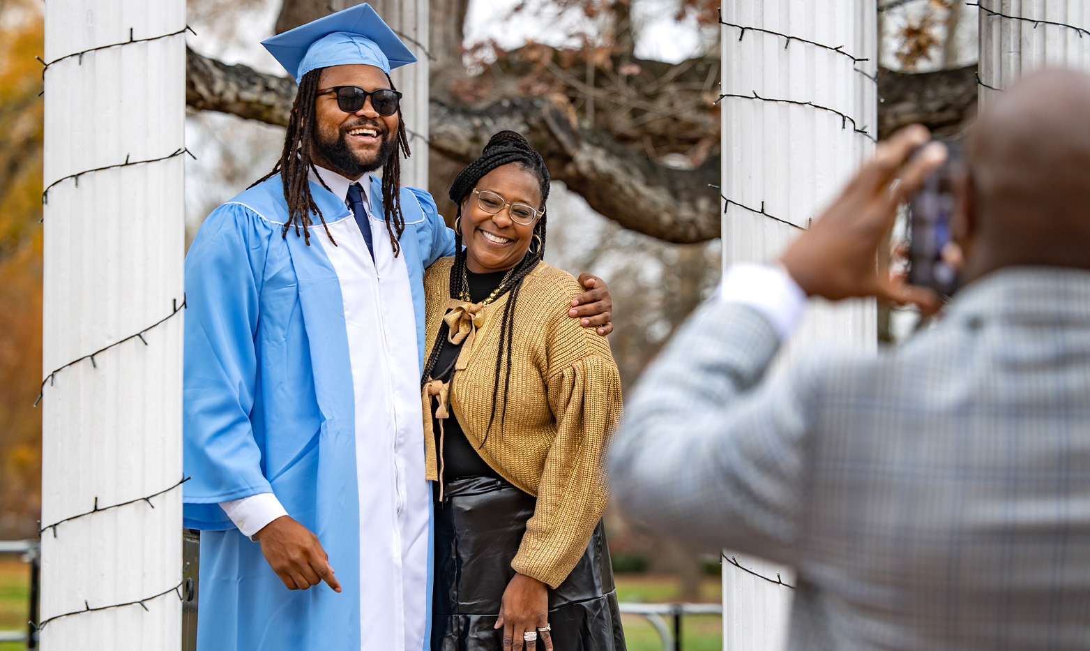 A graduate poses with a family member by the old well.