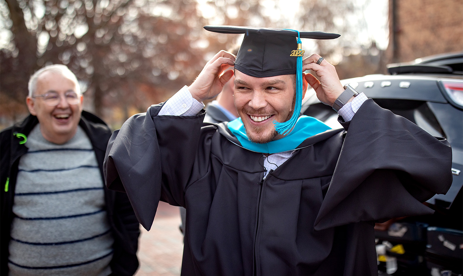 A graduate adjusts his cap.
