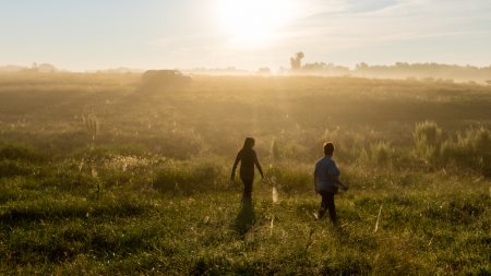 Two people walking across a field at dawn