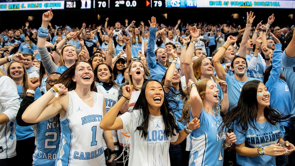 A group of students cheer on the basketball team in the Dean Smith Center