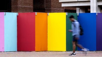 a student walking by colorful painted boards.