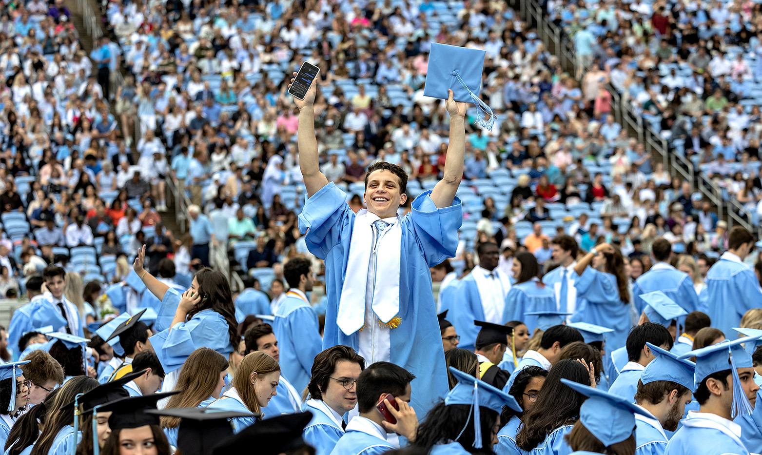 A graduate waving to the crowd.