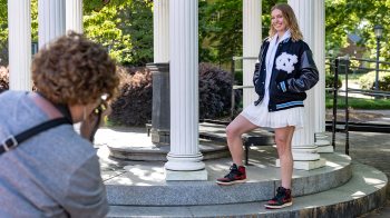 A UNC student poses for a photo in a varsity jacket.