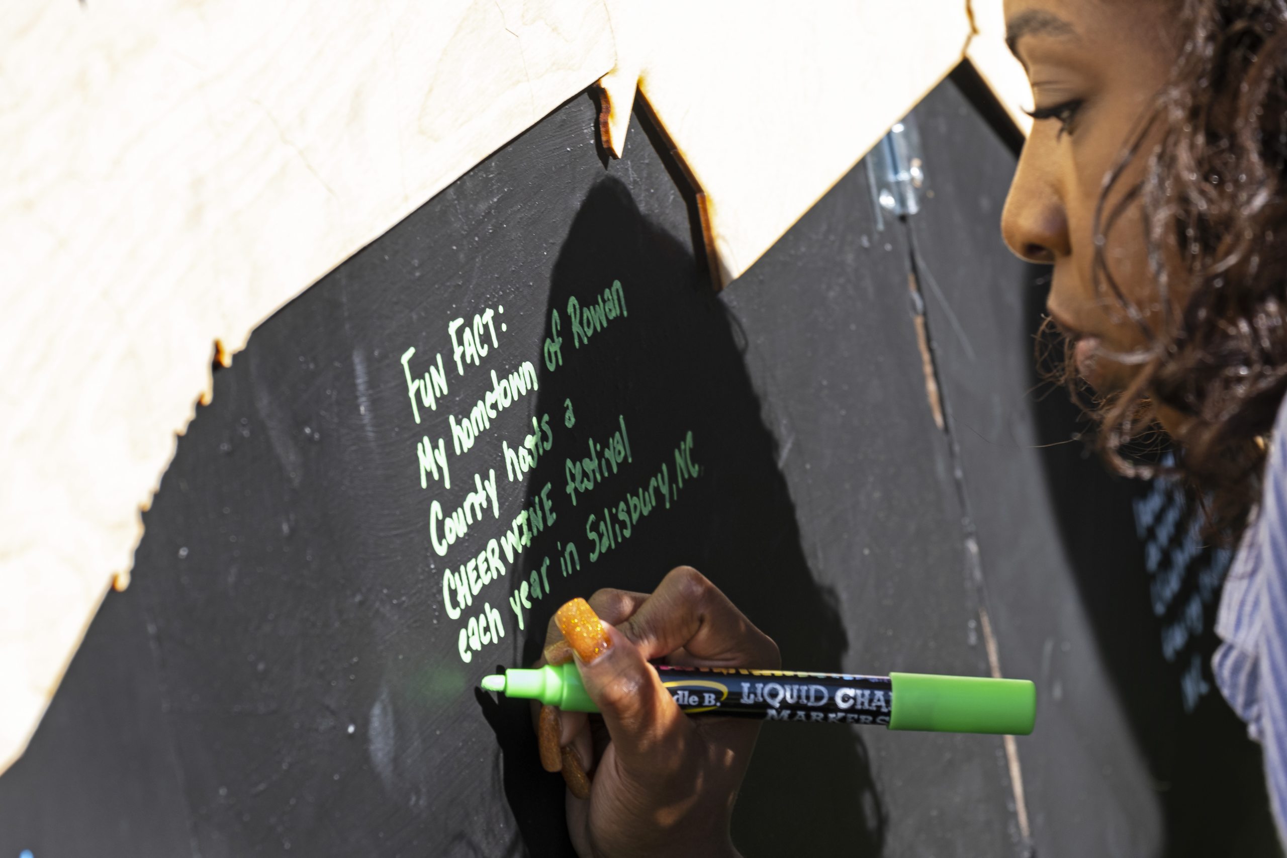 Close-up of Black woman writing a message on a board.