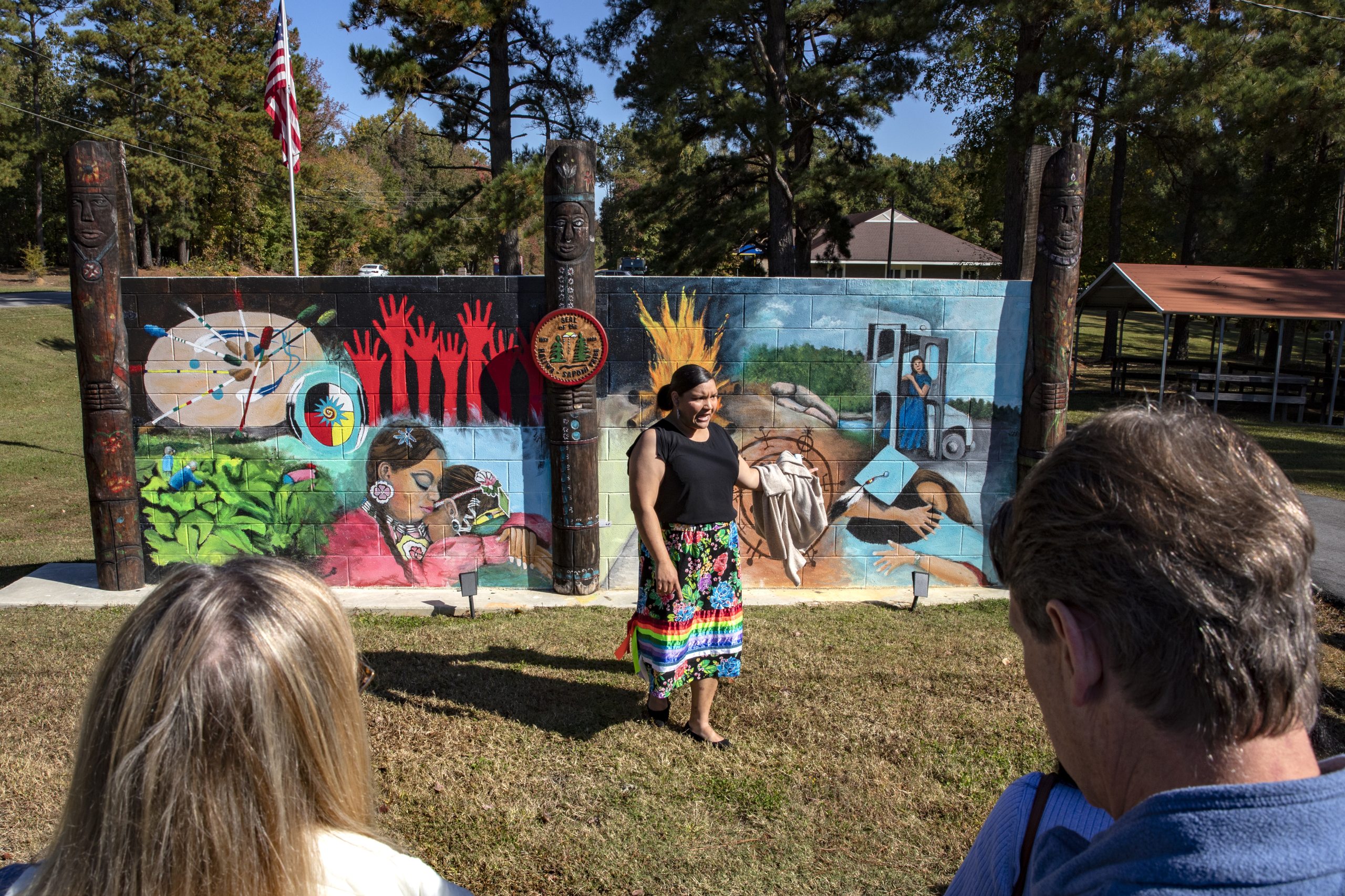American Indian woman speaking in front of a mural