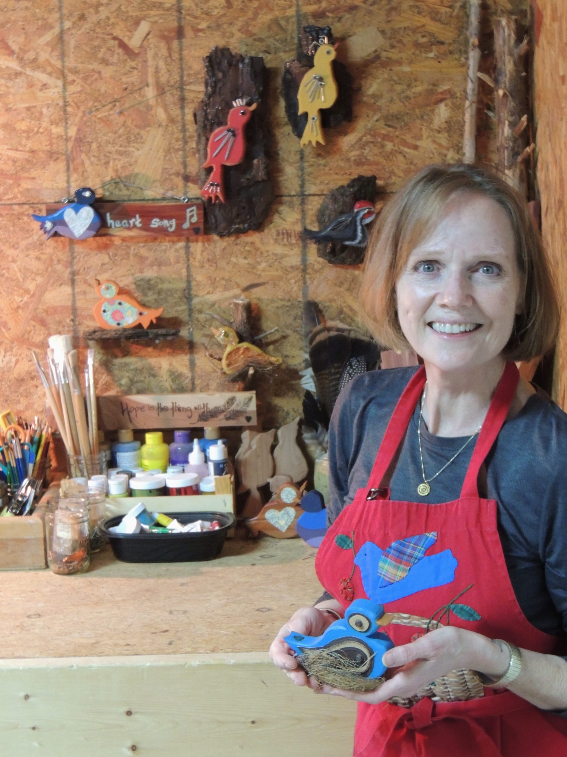 Deborah J. Bousquet holds one of her folk art wooden birds.