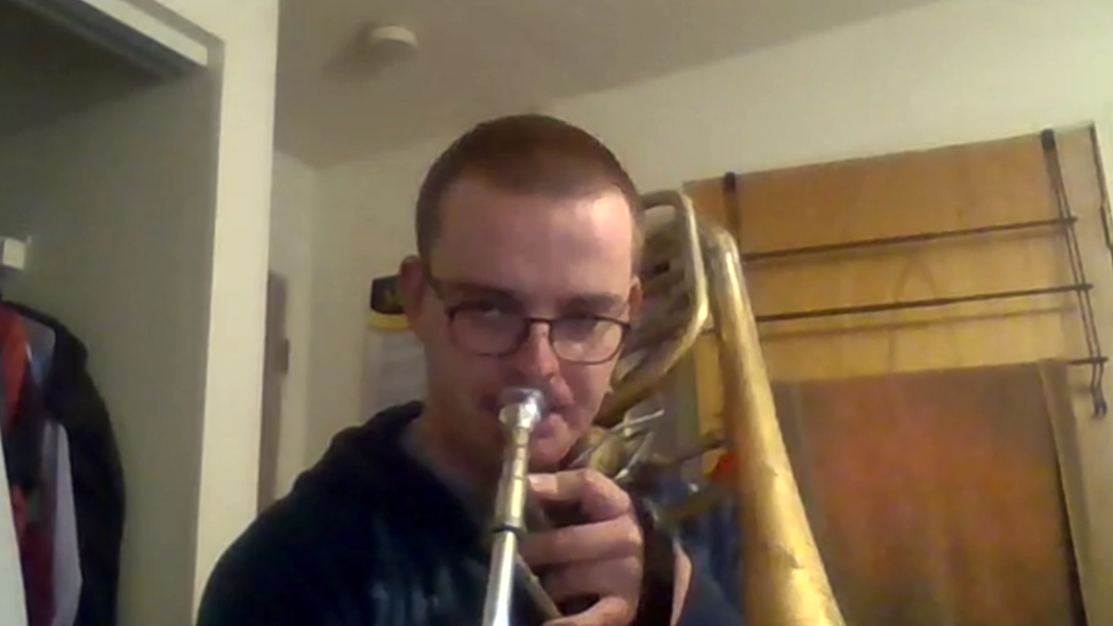 Christian Boletchek plays trombone on a Zoom feed from his bedroom.