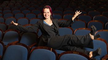 Smiling Alison Friedman perched on theater seats.