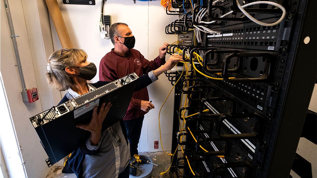 UNC ITS network analysts Len Needhan and Mary Wezyk remove and replace a network switch. Network switches are the key building blocks of Carolina's wireless network that all on-campus employees use. (Jon Gardiner/UNC-Chapel Hill)