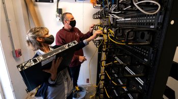 UNC ITS network analysts Len Needhan and Mary Wezyk remove and replace a network switch. Network switches are the key building blocks of Carolina's wireless network that all on-campus employees use. (Jon Gardiner/UNC-Chapel Hill)
