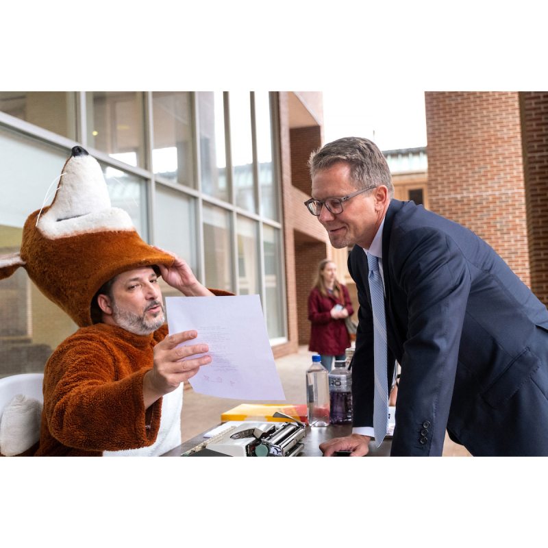 A man in a fox mascot reading a poem he wrote to another man, UNC-Chapel Hill Chancellor Kevin M. Guskiewicz.