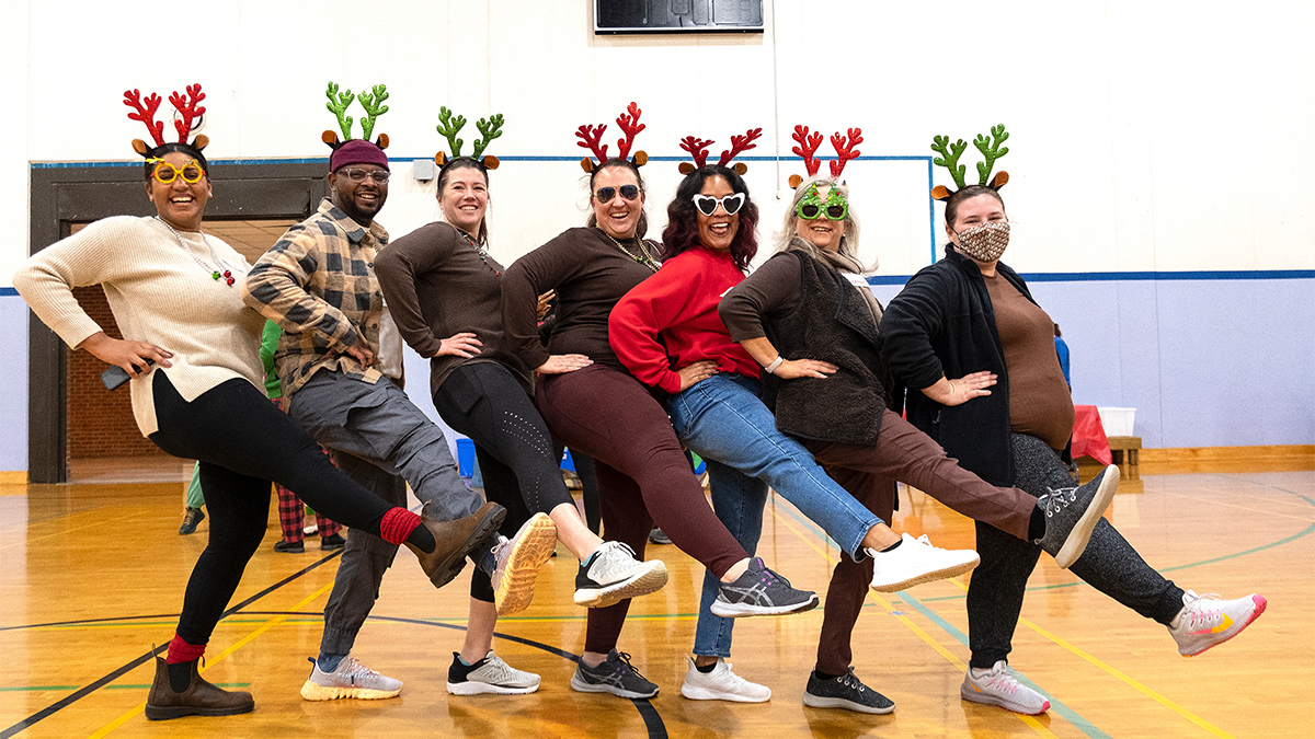 Seven people dressed as reindeer in a dance line.