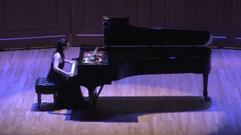 Clara Yang plays a piano on stage