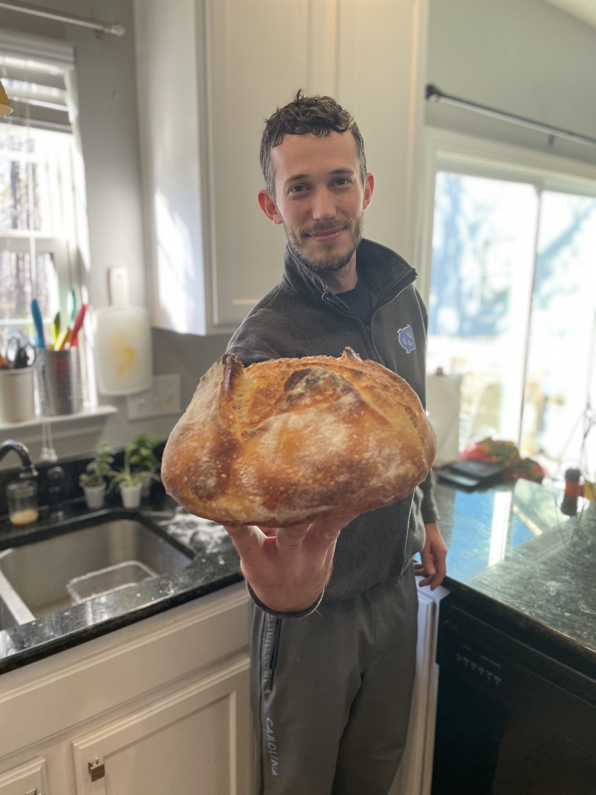 Brett Phillips holds out a loaf of bread that he baked.