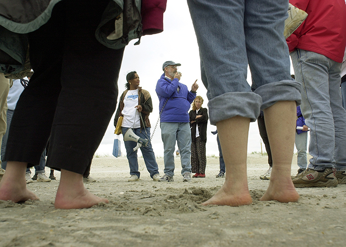 In 2003, the group, many barefooted, stand in the sand of Wrightsville Beach.John Wells, former director of the Carolina’s Institute of Marine Sciences, talks to the group about the Mason Inlet project at Wrightsville Beach. Tour coordinator Linda Douglas stands next to Wells with bullhorn and tour notes in hand. (Dan Sears/UNC-Chapel Hill)