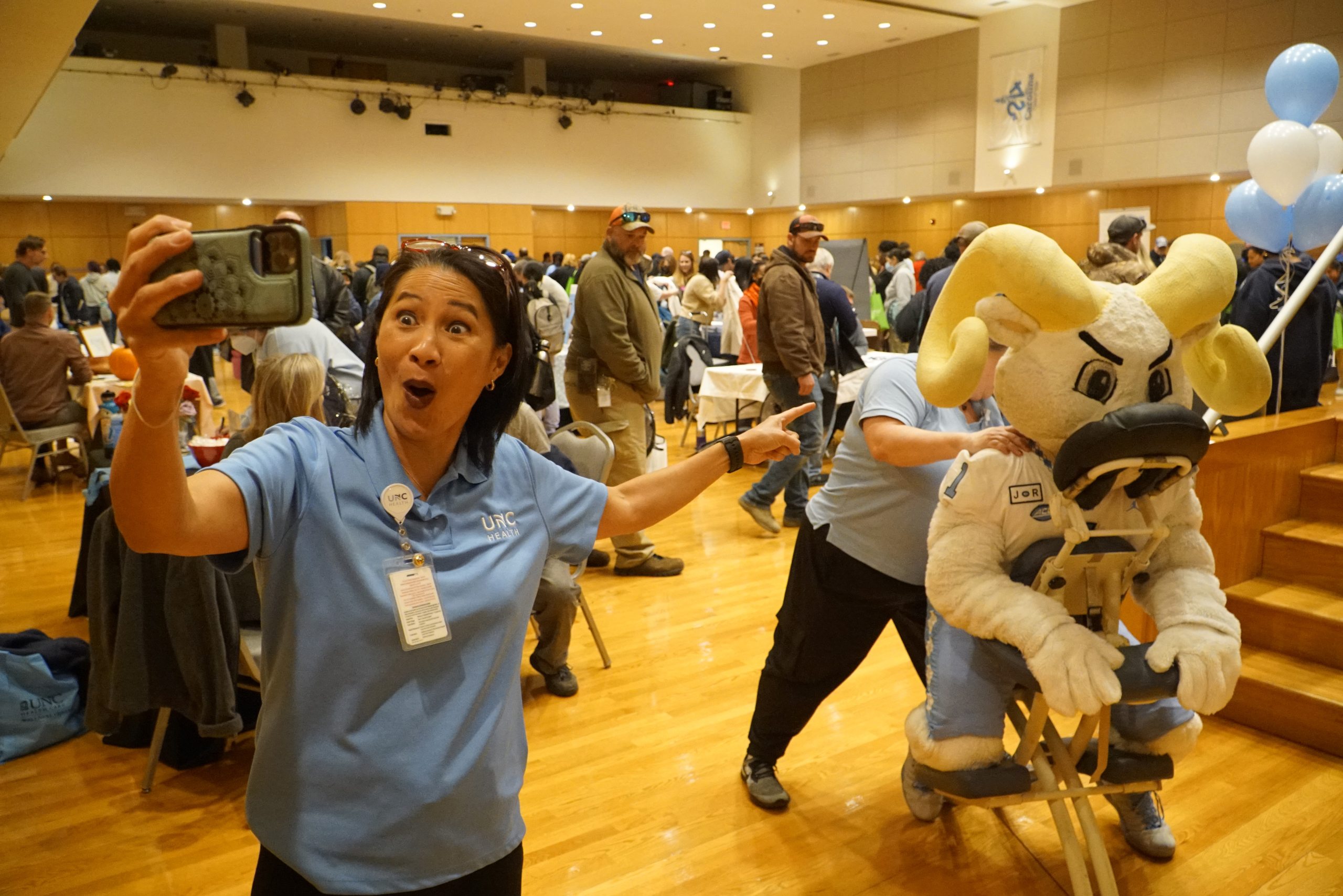 Lori Black, massage therapist with UNC Wellness, works on Rameses, while her UNC Wellness colleague, Jamie McGee snaps a selfie.