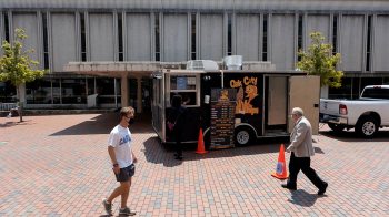 Food truck parked in front of Undergraduate Library with two men walking past.