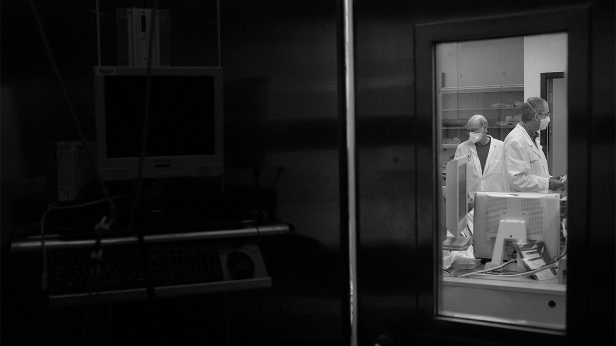 black and white photo of researcher in a lab seen through a door