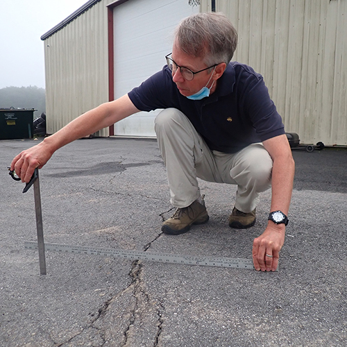 Professor Kevin Stewart measures vertical displacement in a parking lot in Sparta. 