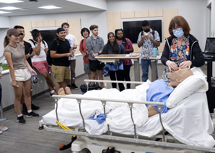 Students in the Summer Bridge program watch as a faculty member in the School of Nursing demonstrates a procedure on a special mannequin.