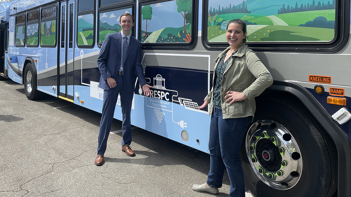 Sustainability analysts Melanie Elliott and R.E.S.P.E.C. co-chair Ben Brown stand beside an electric bus funded by student fees.