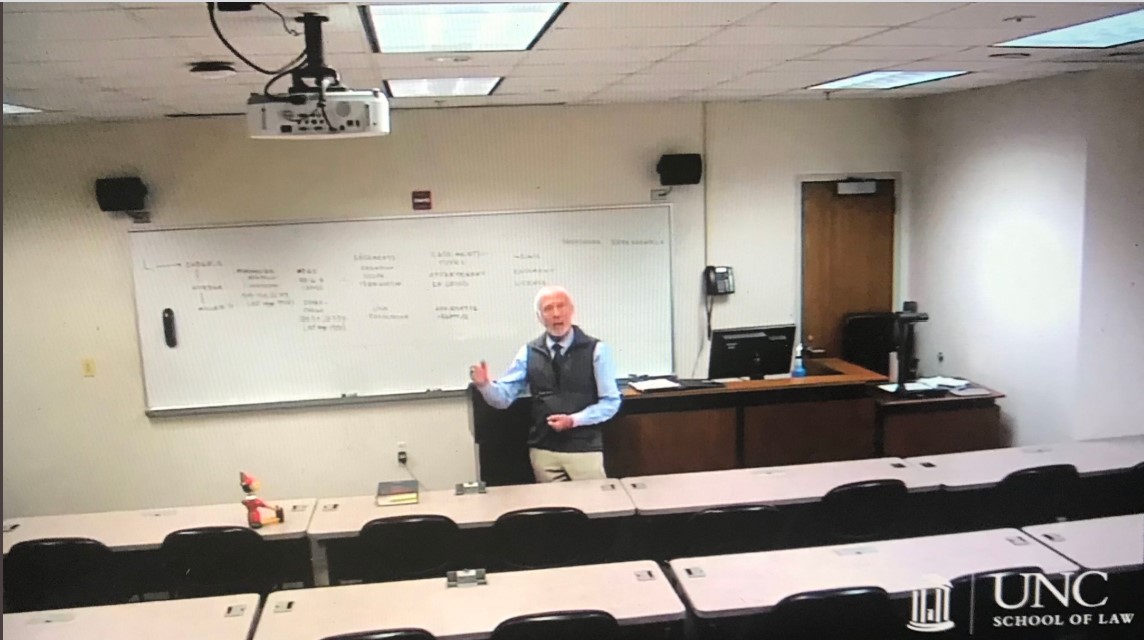 A Twitter screenshot shows John Orth in a pre-recorded lecture with a Pinocchio doll in the front row.