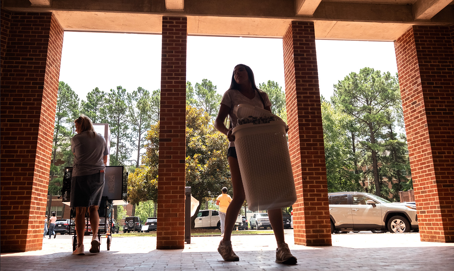 A student holding supplies as she walks into a dormitory building.