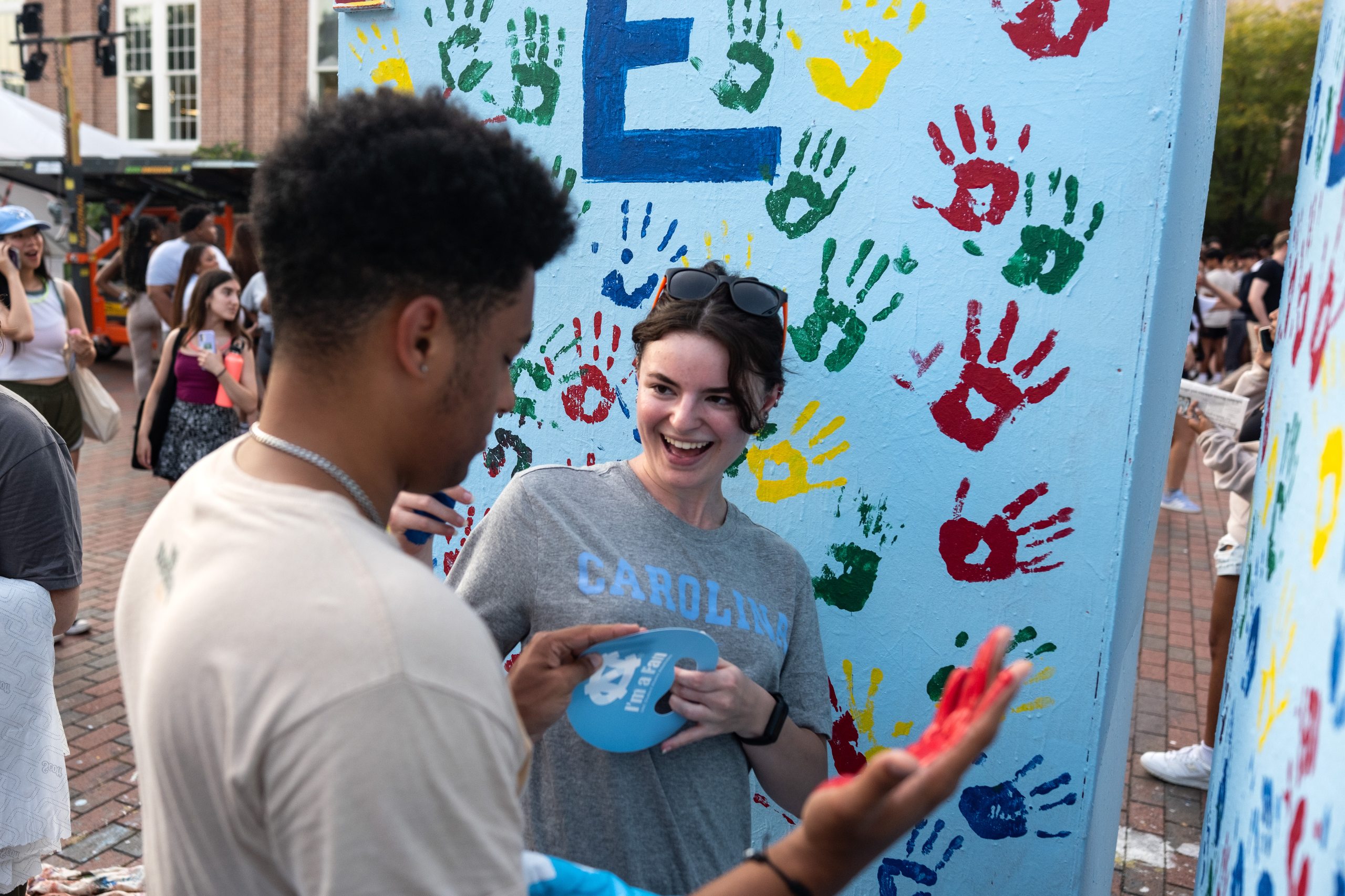 Two students preparing to paint a canvas with their hand prints.