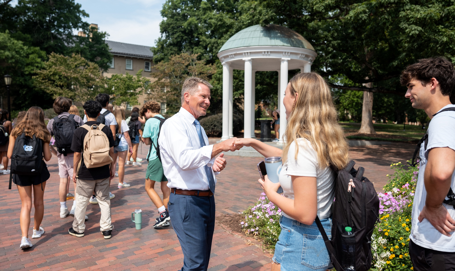 A man, UNC-Chapel Hill Chancellor Kevin M. Guskiewicz, gives a student a fist bump.