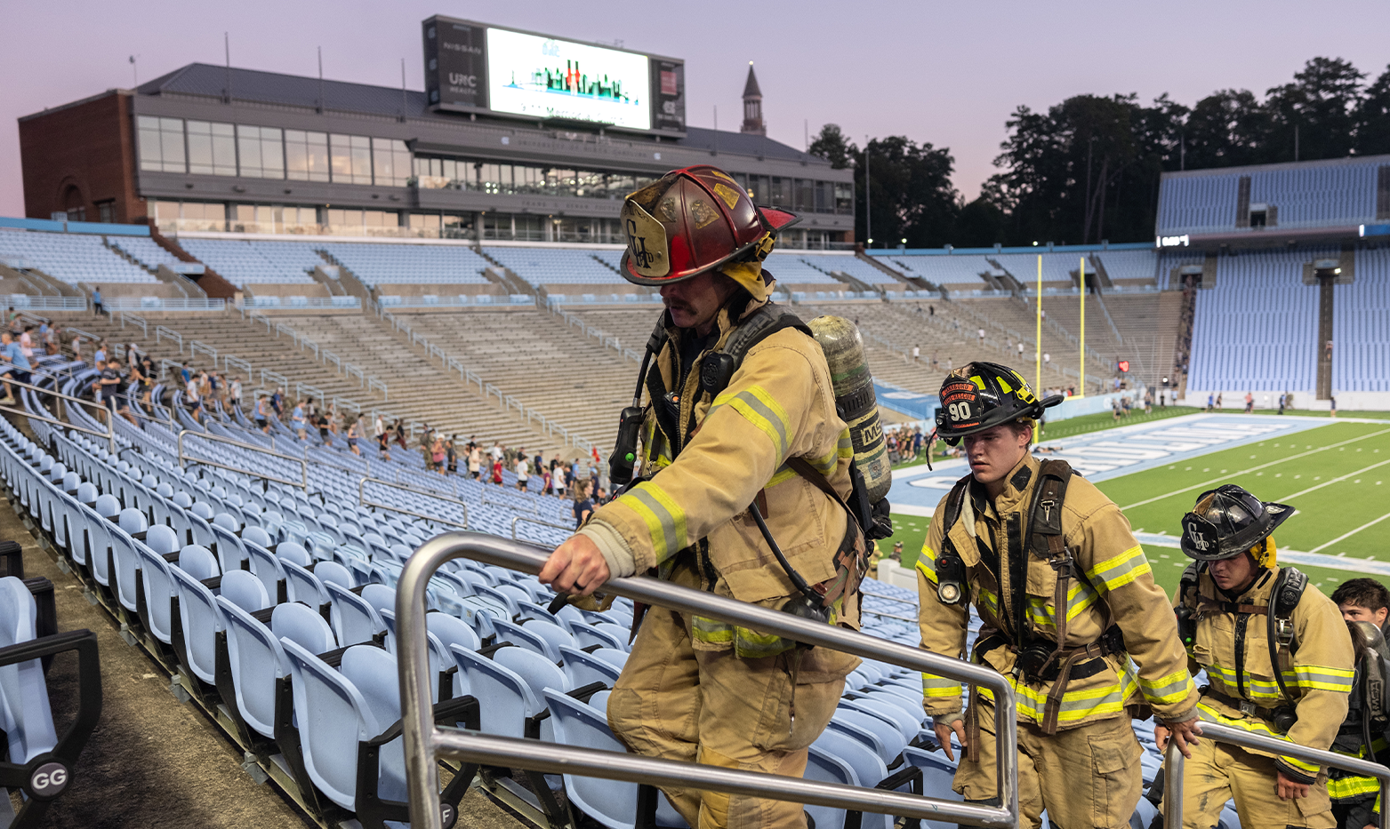 Three firefighters running up stadium steps at dawn.
